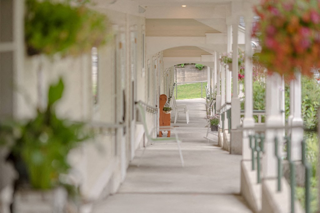 a long hallway with white pillars and flowers on the end of it