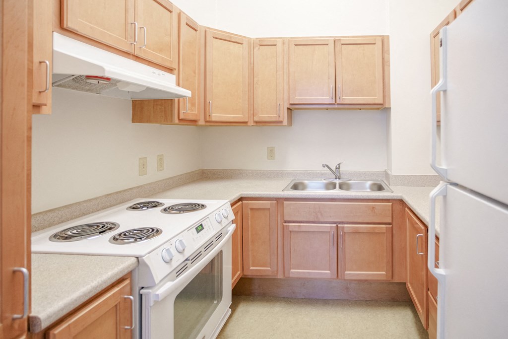 a kitchen with wood cabinets and white appliances and a stove top oven
