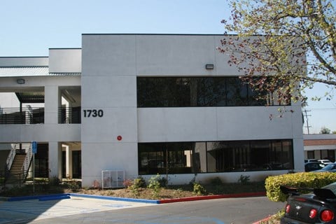 an office building with a parking lot and a tree