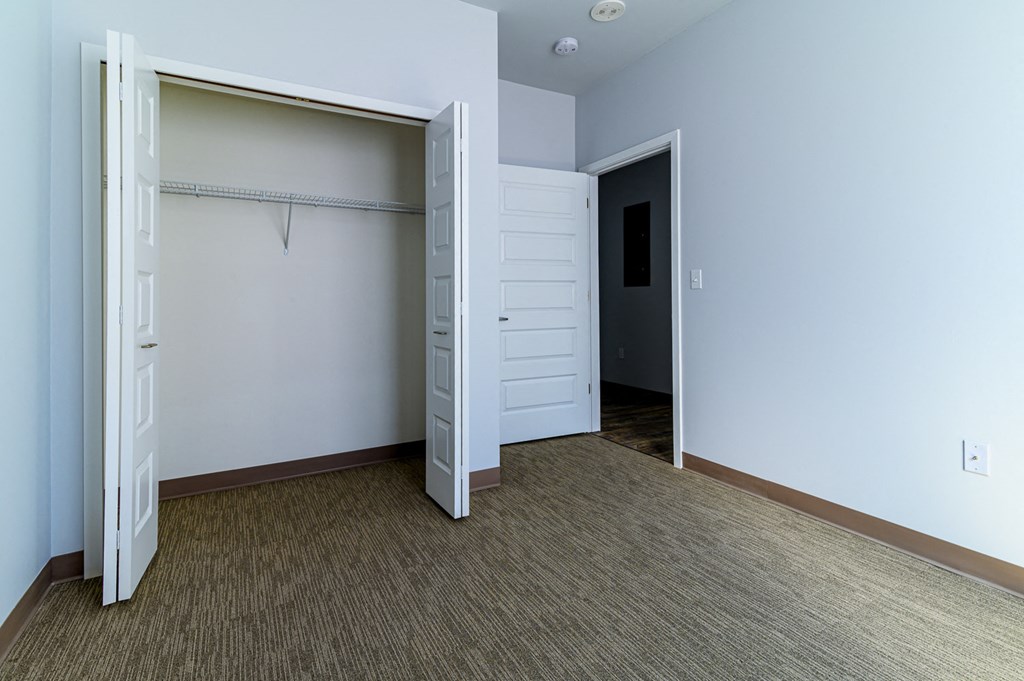 an empty bedroom with a closet and a door open