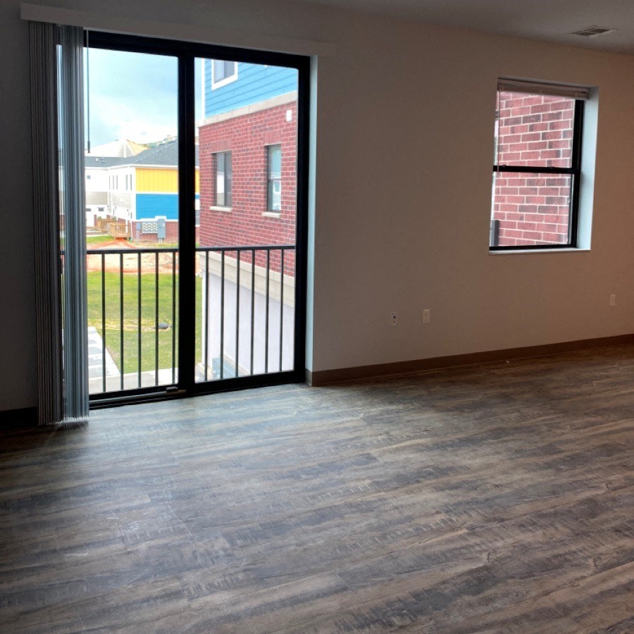 an empty living room with a sliding glass door and a balcony
