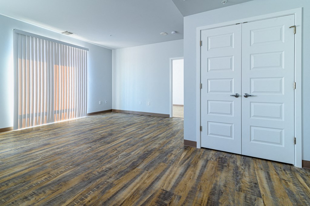 an empty living room with a white door and wood flooring