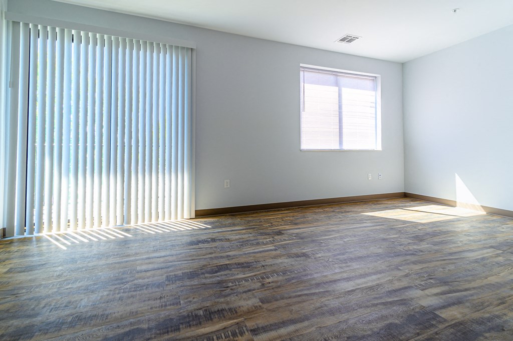 an empty living room with a large window and wood floors