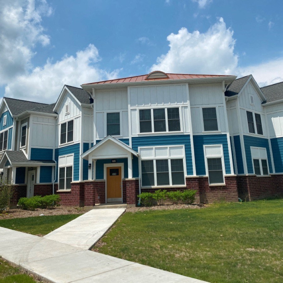 a blue and white house with a sidewalk in front of it