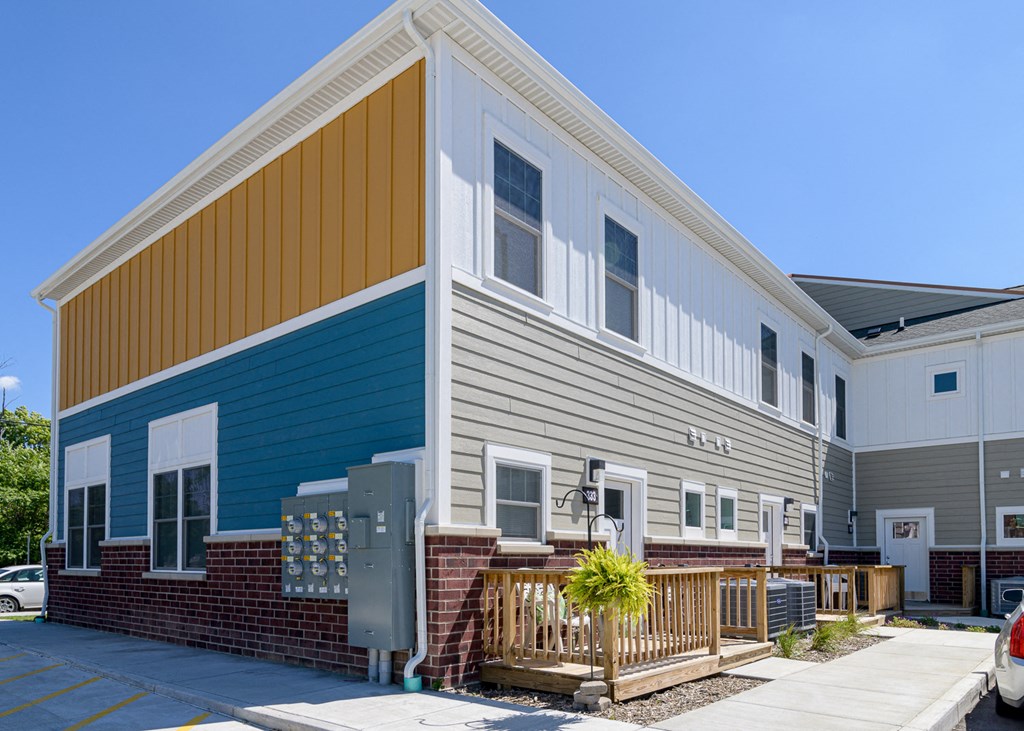 the front of an apartment building with a porch and a sidewalk