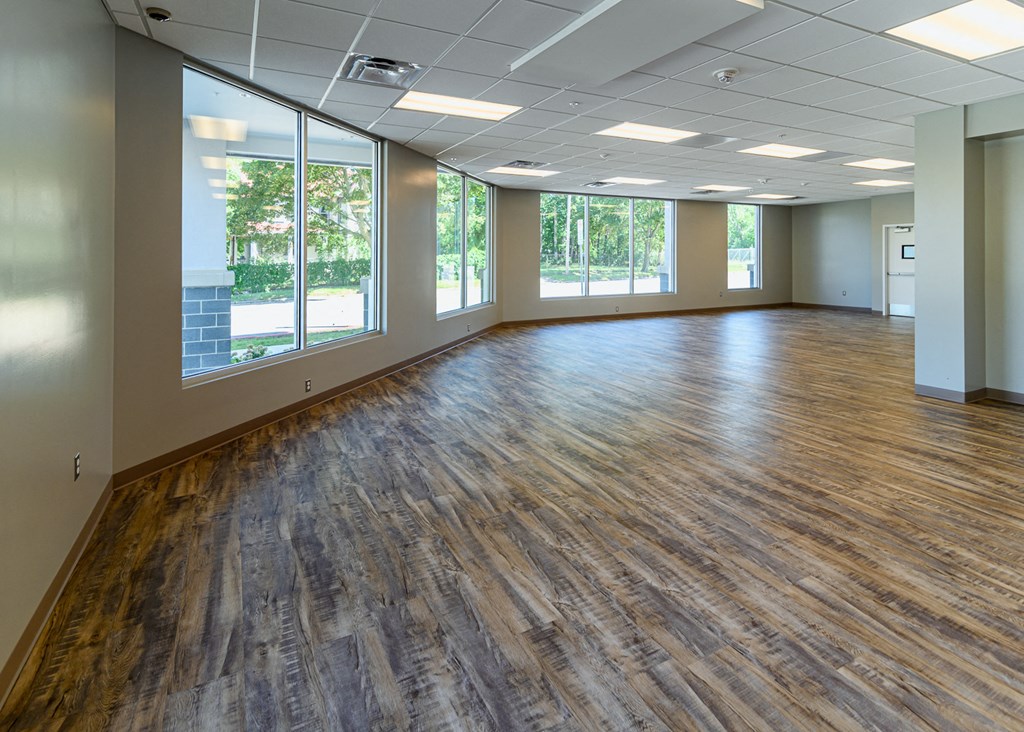 an empty room with a wood floor and large windows