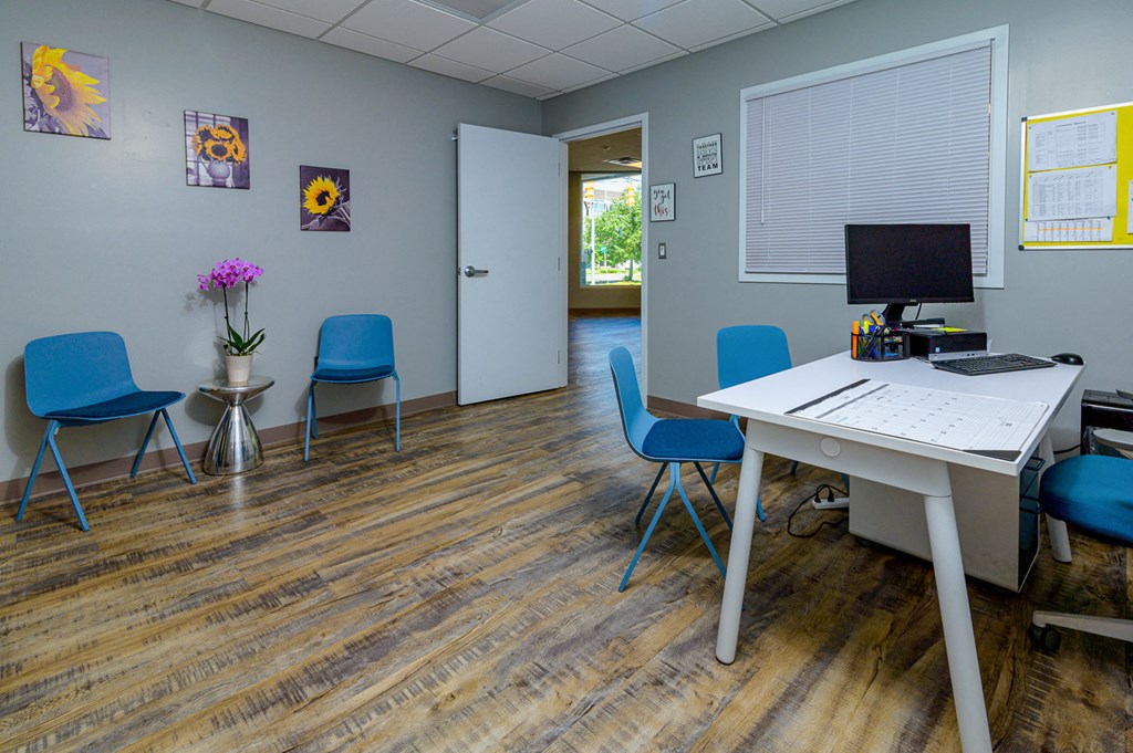 a therapy room with a computer and chairs and a table