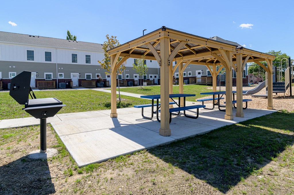 a picnic area with a wooden pavilion and picnic tables