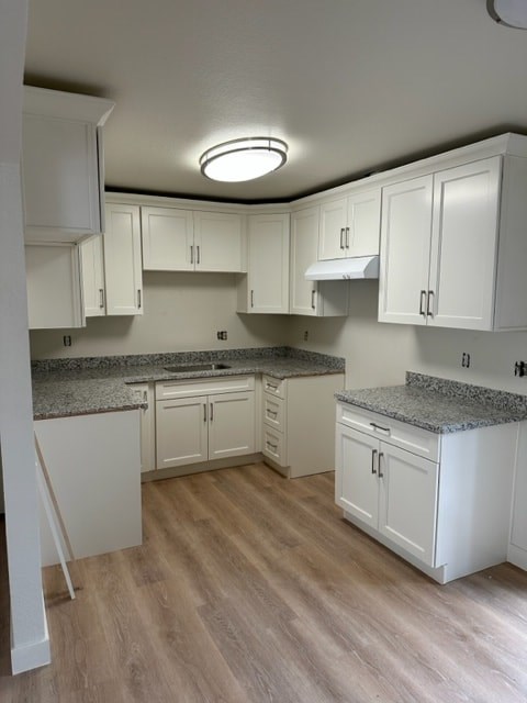 A kitchen with white cabinets and a granite countertop.