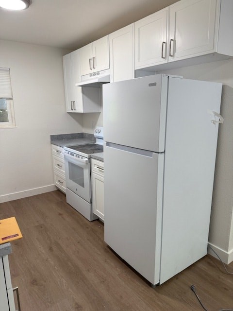 A white refrigerator is in a kitchen with white cabinets.