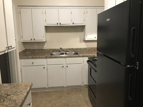 a kitchen with white cabinets and a sink and a refrigerator
