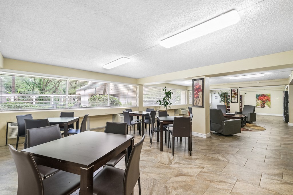 a dining room with tables and chairs and a living room with a large window