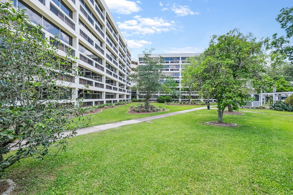 an apartment building with grass and trees in front of it