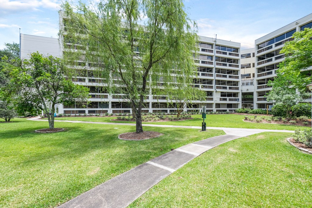 a park in front of an apartment building with grass and trees