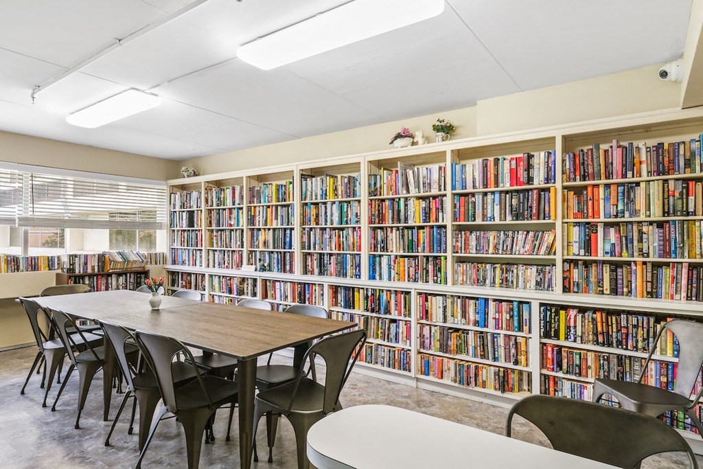 a library with a table and chairs in front of a book shelf