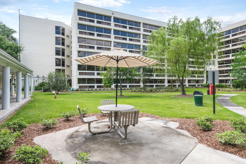 a picnic table with an umbrella in front of an apartment building
