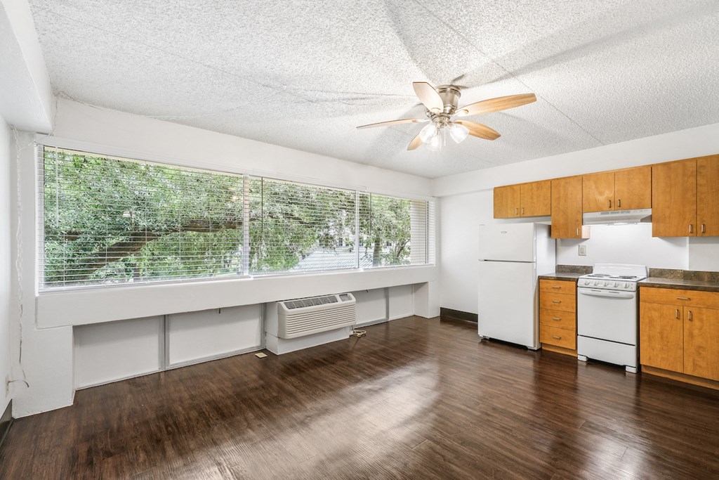 an empty kitchen with a ceiling fan and a large window