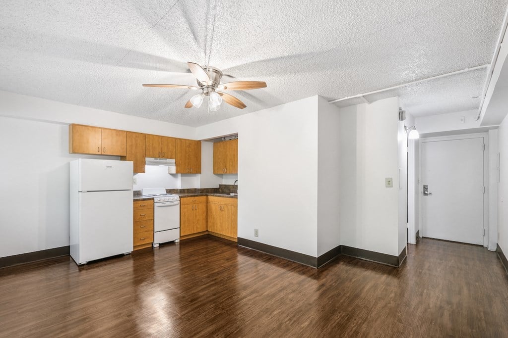 an empty kitchen with white appliances and a ceiling fan