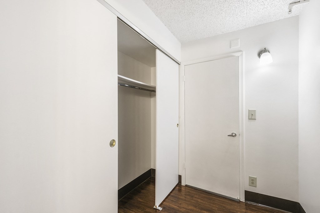 an empty room with white walls and a door to a closet
