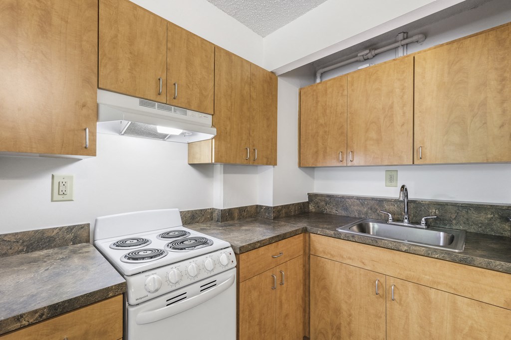 a kitchen with a stove and sink and wooden cabinets