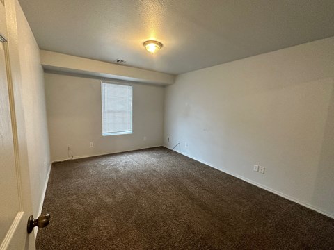 A room with a carpeted floor and a window with blinds.