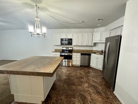 A kitchen with a wooden counter top and stainless steel appliances.
