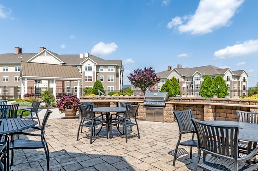 a patio with tables and chairs and a grill