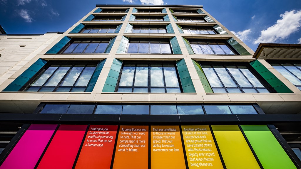 a tall building with different colors of windows and a blue sky