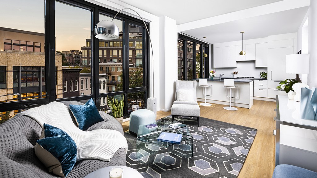 a living room with a couch and a view of a kitchen and a large window