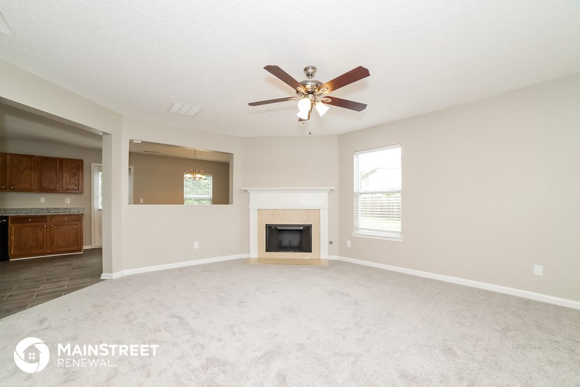 the living room has a fireplace and a ceiling fan