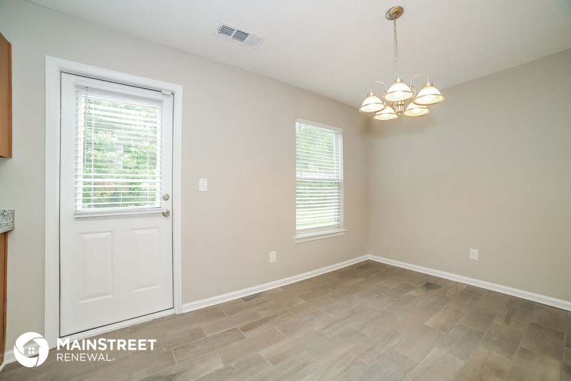 the living room of a home with a white door and tile floor