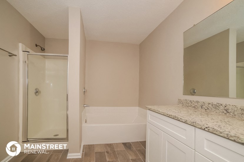 a bathroom with white cabinets and a shower and a sink