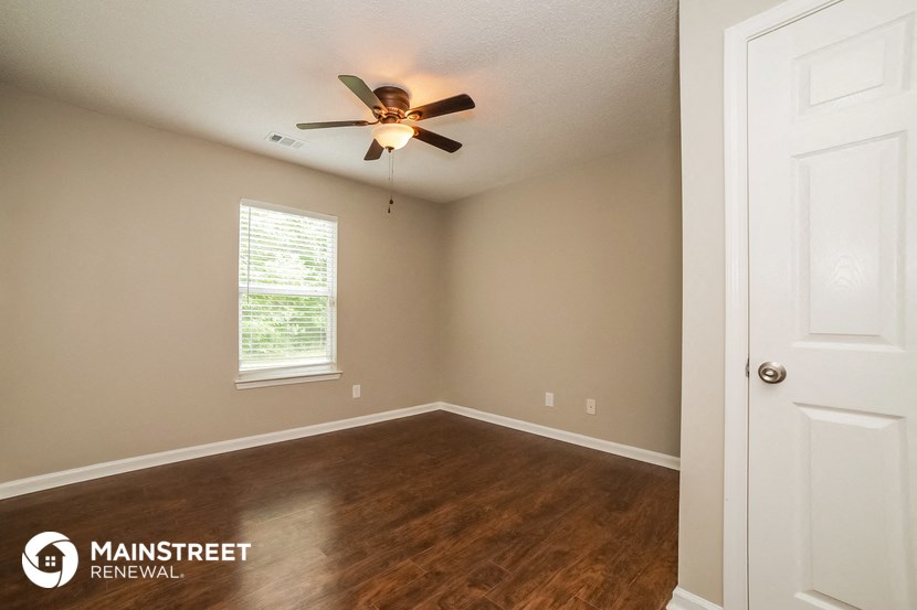 the interior of a bedroom with wood flooring and a ceiling fan