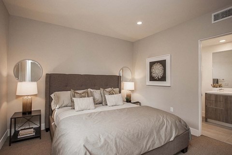 A bedroom with a large bed and a lamp on the side table.