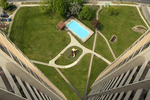 A man is walking in a park with a swimming pool.