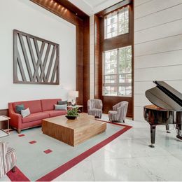 A living room with a red couch, a wooden coffee table, and a grand piano.
