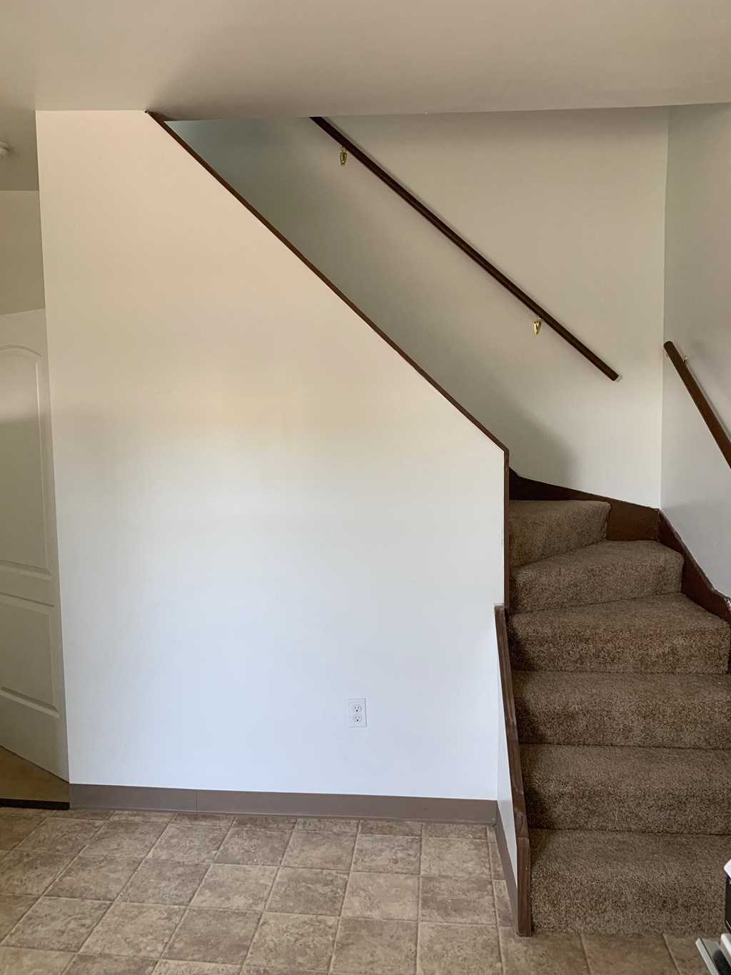 A staircase with a brown carpeted runner and wooden handrails.