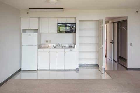 an empty kitchen with white cabinets and a sink and a refrigerator