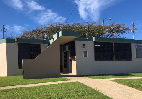 a house with a green and white facade and a sidewalk