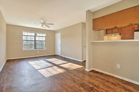an empty living room with a ceiling fan and a window