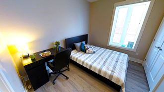 a bedroom with a bed and a desk and a window