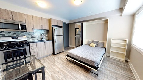 a bedroom with a bed and a kitchen with stainless steel appliances