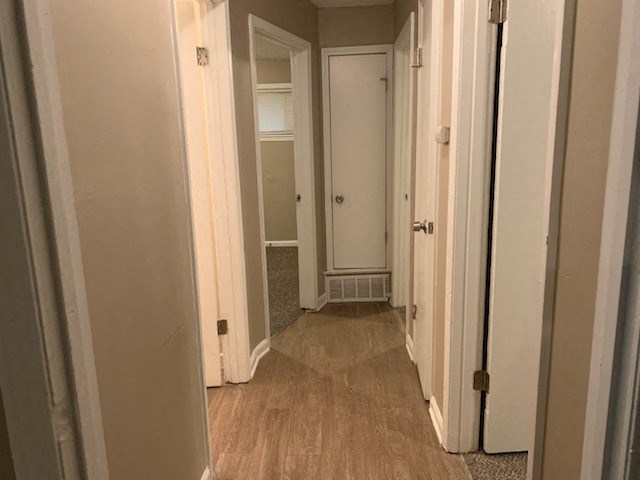 a hallway with three doors and a wood floor