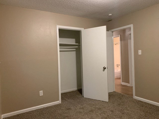 an empty bedroom with a closet and a door open