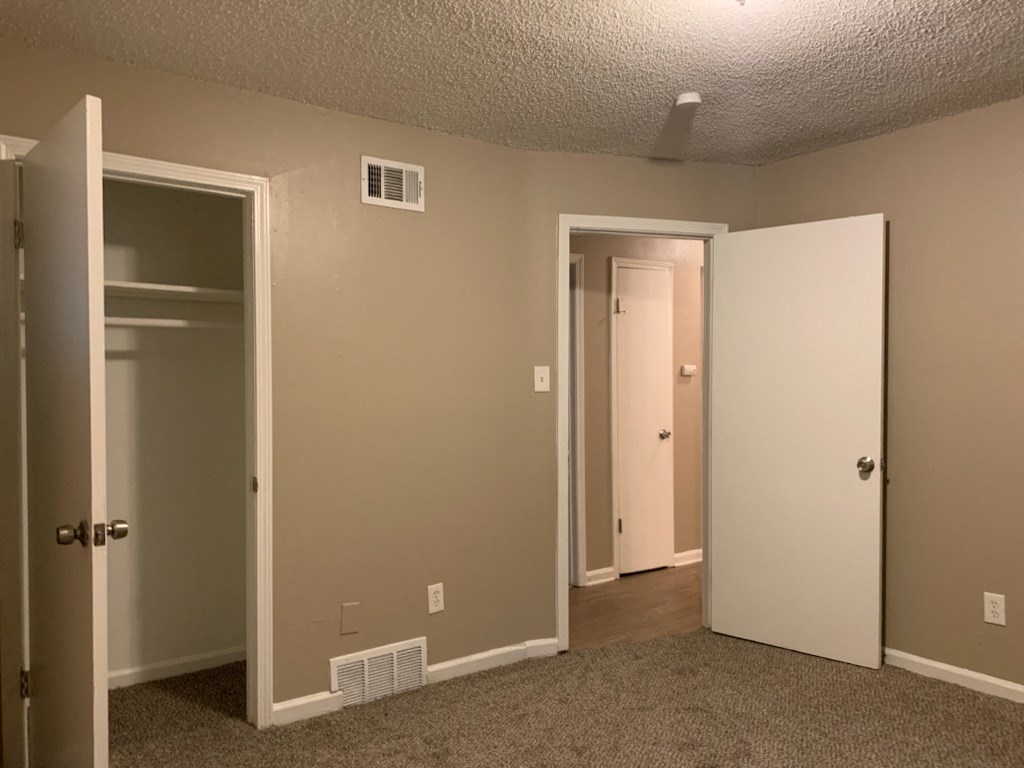 a bedroom with a door open and a closet