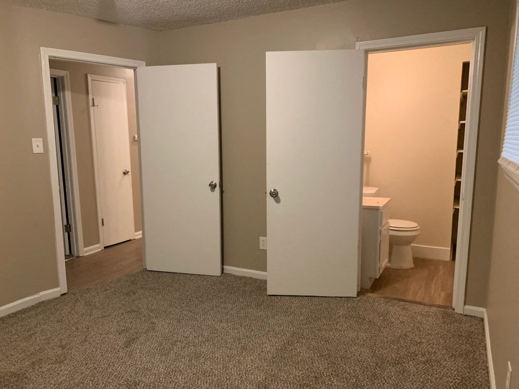 a bedroom with three doors and a bathroom with a toilet
