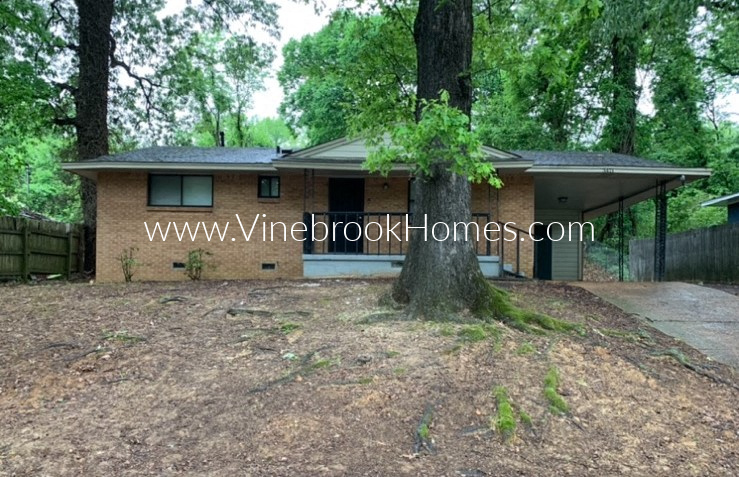 a small brick house with a tree in front of it