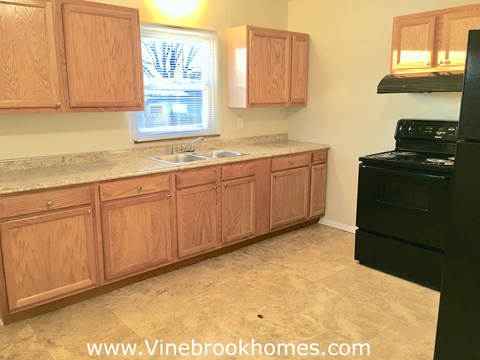 A kitchen with wooden cabinets and a black stove.