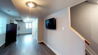 a living room with a tv on the wall and a wooden floor