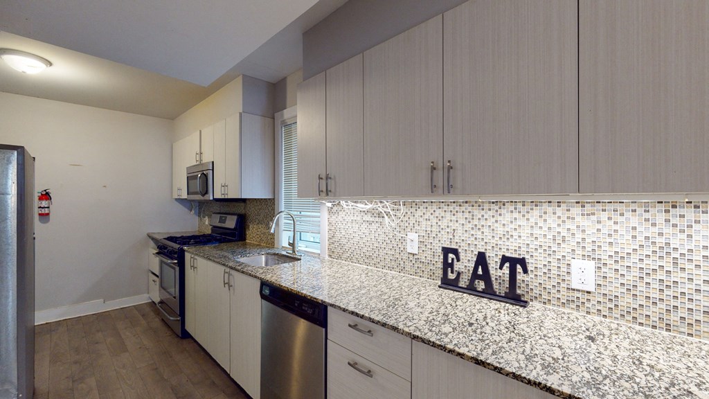 a kitchen with white cabinets and a counter with a eat sign